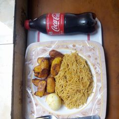 A picture of Jollof pasta and fried plantain with boiled egg.