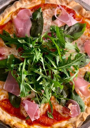 Une photo de Pizza jambon italien roquette