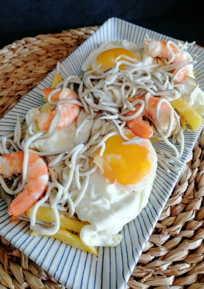 Una foto de Huevos rotos con gulas y langostinos