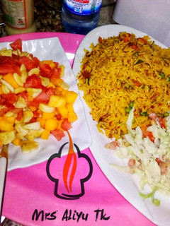 A picture of Jalof rice with coleslow and fruits salad.