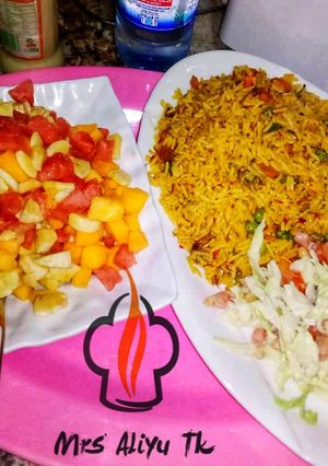 A picture of Jalof rice with coleslow and fruits salad.