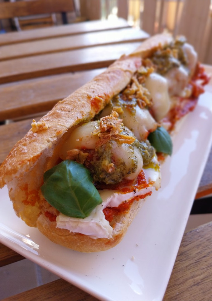Una foto de Bocata de albóndigas gratinadas en salsa de tomate con camembert y pesto