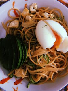 Una foto de Espaguetis integrales con espaguetis de calabacín, aguacate, tofu y huevo poché