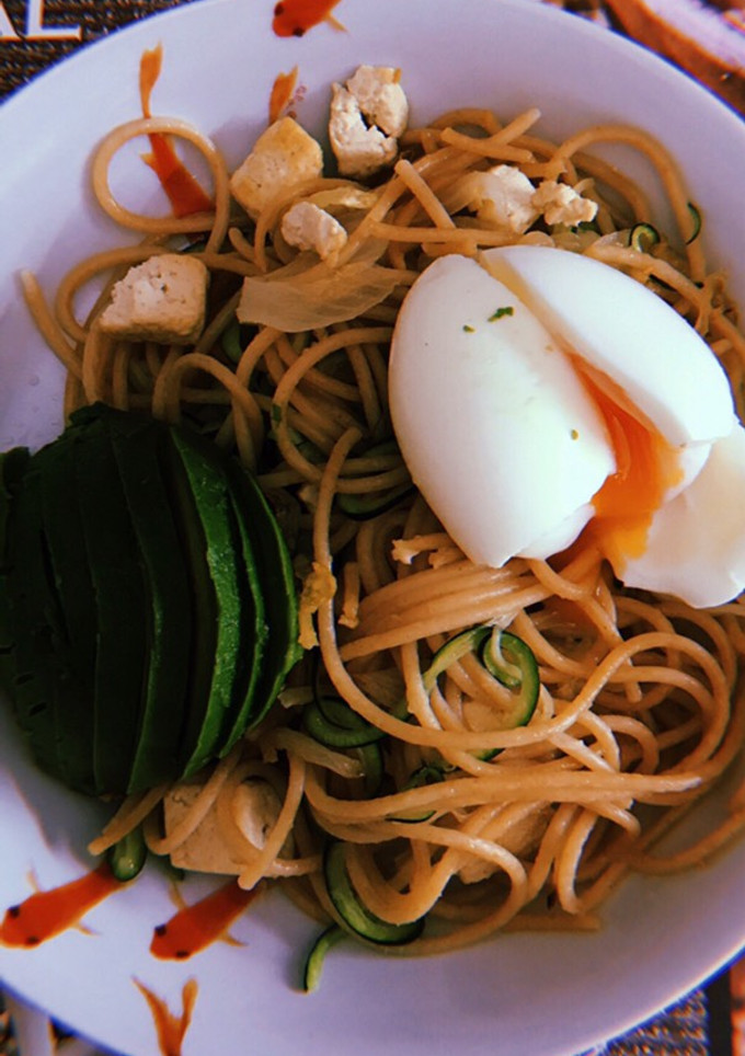 Una foto de Espaguetis integrales con espaguetis de calabacín, aguacate, tofu y huevo poché