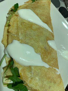 Una foto de Tortilla media luna con tomate, aguacate, rúcula y queso. Topping de salsa de yogur