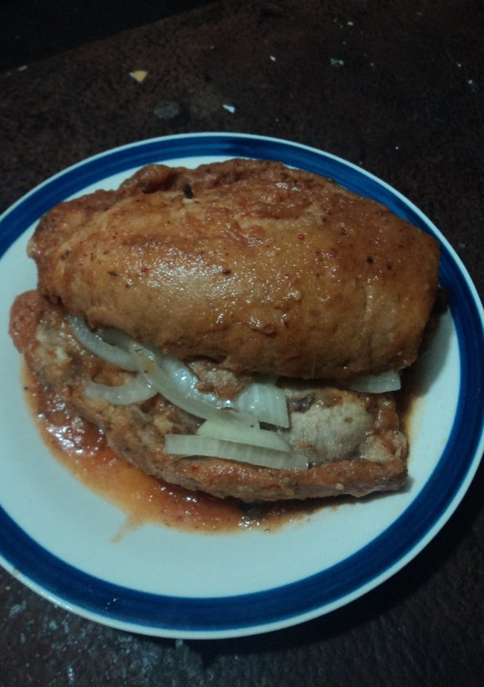 Una foto de Torta bañada en jitomate,  carnitas de cerdo con cebolla desflemada estilo las Correa de San Diego