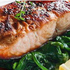 A picture of Salmon with thyme on bed of spinach.