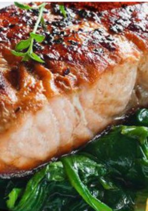 A picture of Salmon with thyme on bed of spinach.