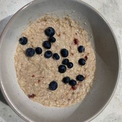 A picture of Porridge with blueberries and strawberry jam.