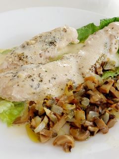 Una foto de Pollo en salsa holandesa sobre lechuga y setas con cebolla