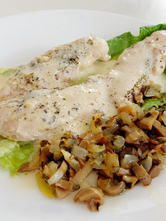 Una foto de Pollo en salsa holandesa sobre lechuga y setas con cebolla