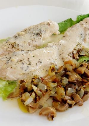 Una foto de Pollo en salsa holandesa sobre lechuga y setas con cebolla