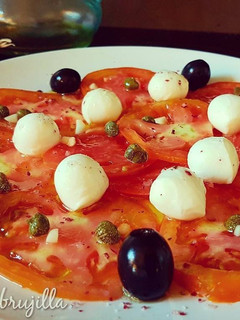 Una foto de Carpaccio de tomate con perlas de mozzarella