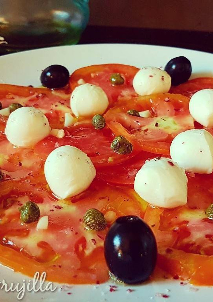 Una foto de Carpaccio de tomate con perlas de mozzarella