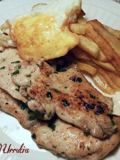 Una foto de Filetes de pollo especiados, con patatas fritas y huevo con yema frita