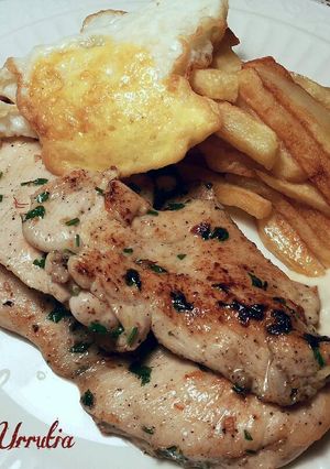 Foto principal de Filetes de pollo especiados, con patatas fritas y huevo con yema frita