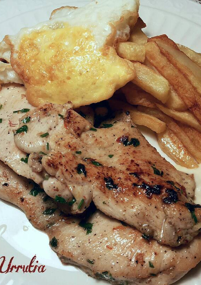Una foto de Filetes de pollo especiados, con patatas fritas y huevo con yema frita
