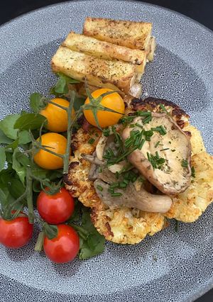 A picture of Curry Dusted Cauliflower ‘Steak’ Topped With Chive and Garlic Mushrooms.