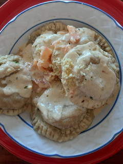 Una foto de Sorrentinos de pollo-queso y espinaca-queso con crema y tomates