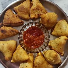 A picture of Samosa with spicy red chutney.