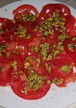Una foto de Carpaccio de tomate con vinagreta de pistachos