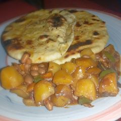 A picture of Naan bread nd potatoe with baked beans sauce.