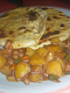 A picture of Naan bread nd potatoe with baked beans sauce.