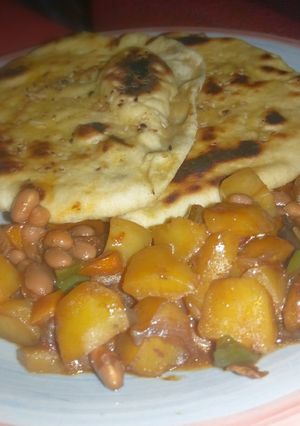 A picture of Naan bread nd potatoe with baked beans sauce.