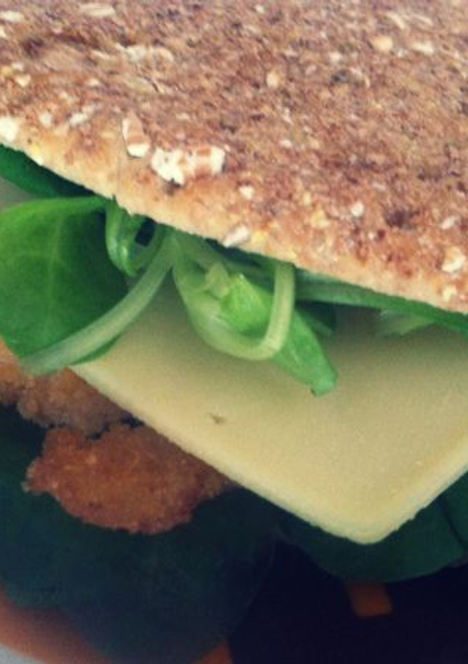 Una foto de Sandwich de pollo empanado con queso, canónigos y salsa césar