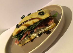Una foto de Ciabatta con relleno de Queso de cabra con especias, jamón serrano, espinacas y crema de balsámico