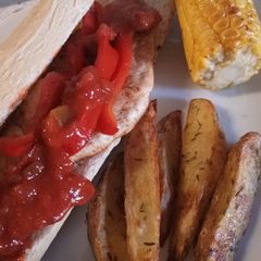 A picture of Spicy Cajun chicken with potato wedges and buttered corn.