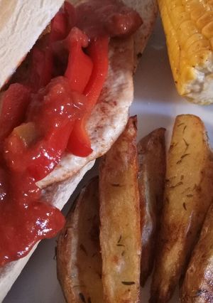 A picture of Spicy Cajun chicken with potato wedges and buttered corn.