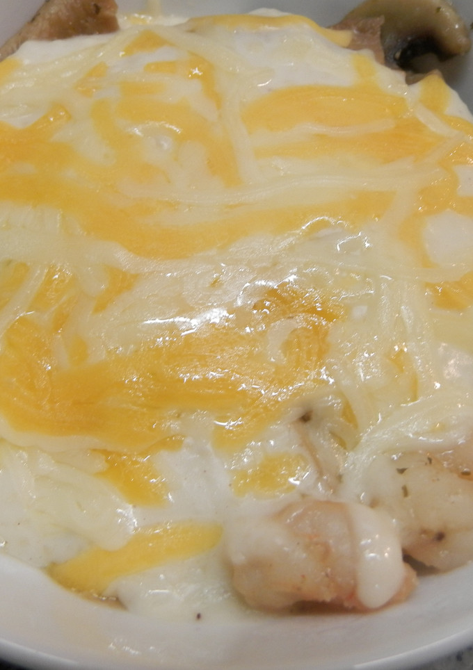 Una foto de gambas,setas y champiñones gratinados con bechamel.