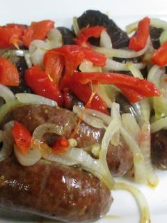 Una foto de Chorizos al horno con cebolla caramelizada y pimientos asados