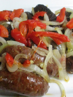 Una foto de Chorizos al horno con cebolla caramelizada y pimientos asados