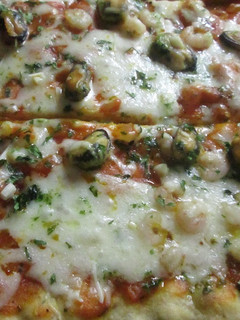 Una foto de Pizza casera con mariscos y salsa verde de ajo y perejil