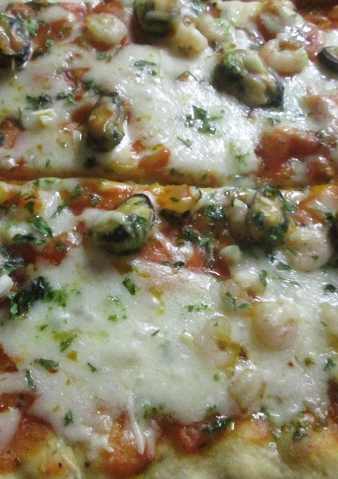 Una foto de Pizza casera con mariscos y salsa verde de ajo y perejil