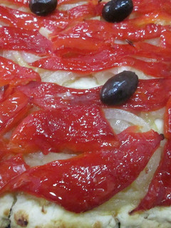 Una foto de Coca de cebolla caramelizada y pimientos asados