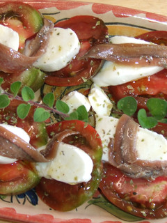Una foto de Ensalada de tomates negros con mozzarella y anchoas