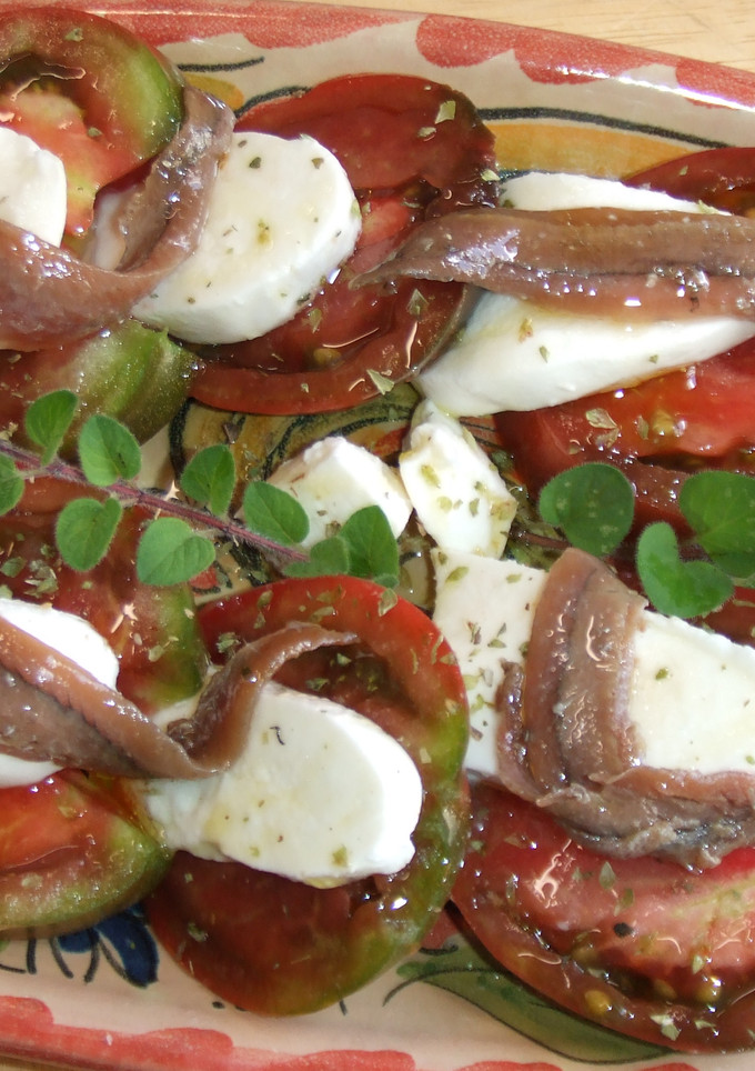 Una foto de Ensalada de tomates negros con mozzarella y anchoas