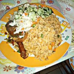 A picture of Jollof Rice garnished with cucumber and cabbage.