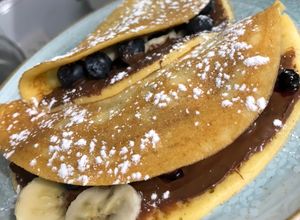 Una foto de Crepe relleno de almíbar de frutos rojos, Nutella y banano