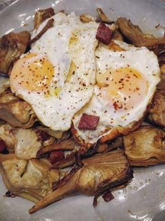 Una foto de Huevos rotos con alcachofas