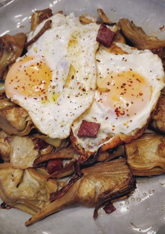 Una foto de Huevos rotos con alcachofas