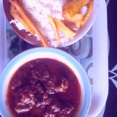 A picture of Rice and tomatoes stew with potatoes chips.