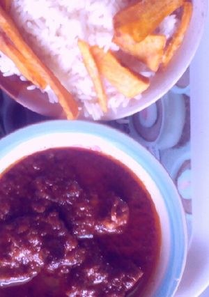 A picture of Rice and tomatoes stew with potatoes chips.