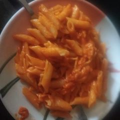 A picture of Red sauce pasta with water.