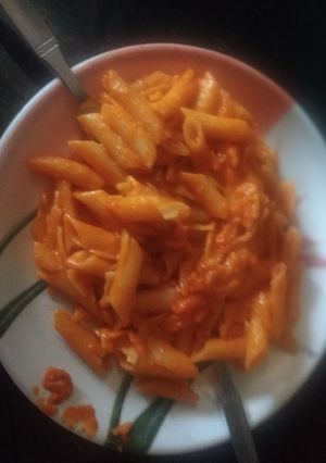 A picture of Red sauce pasta with water.