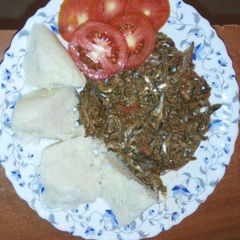 A picture of Ugali served with Omena and garnished with tomato.