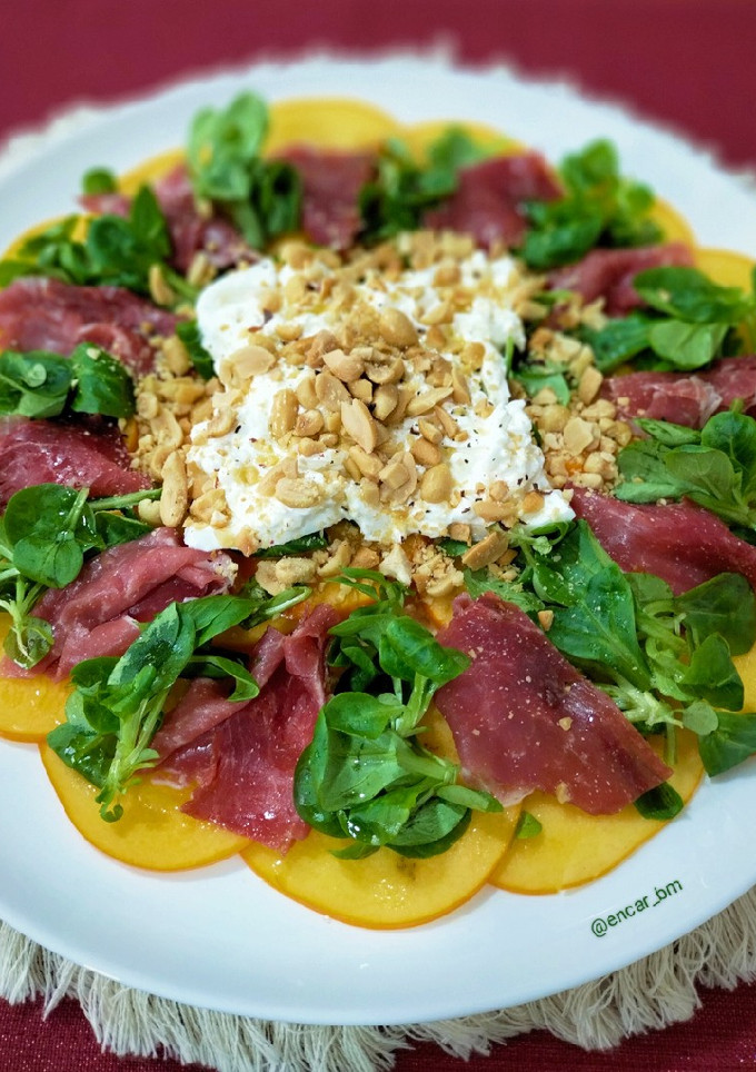 Una foto de Carpaccio de caqui con jamón ibérico, burrata y frutos secos